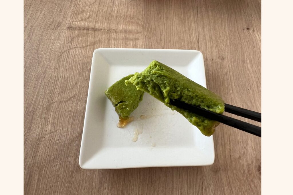 小松菜のお浸しのムースを箸で持ち上げたところ。濃い緑色をしている